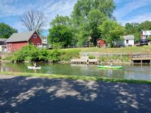 Two canoes are seen headed upstream in a small river.
