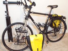 Feedback Sports, 'Sport Mechanic' work stand. Very strong but heavy for a portable stand. I'm exactly six feet tall with normal proportions and the bike fits fine. I wear size 11 SPD shoes and there's no heel clearance issue with the rear bags.