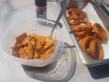 Potato wedge poutine with bacon bits and onion rings on the side