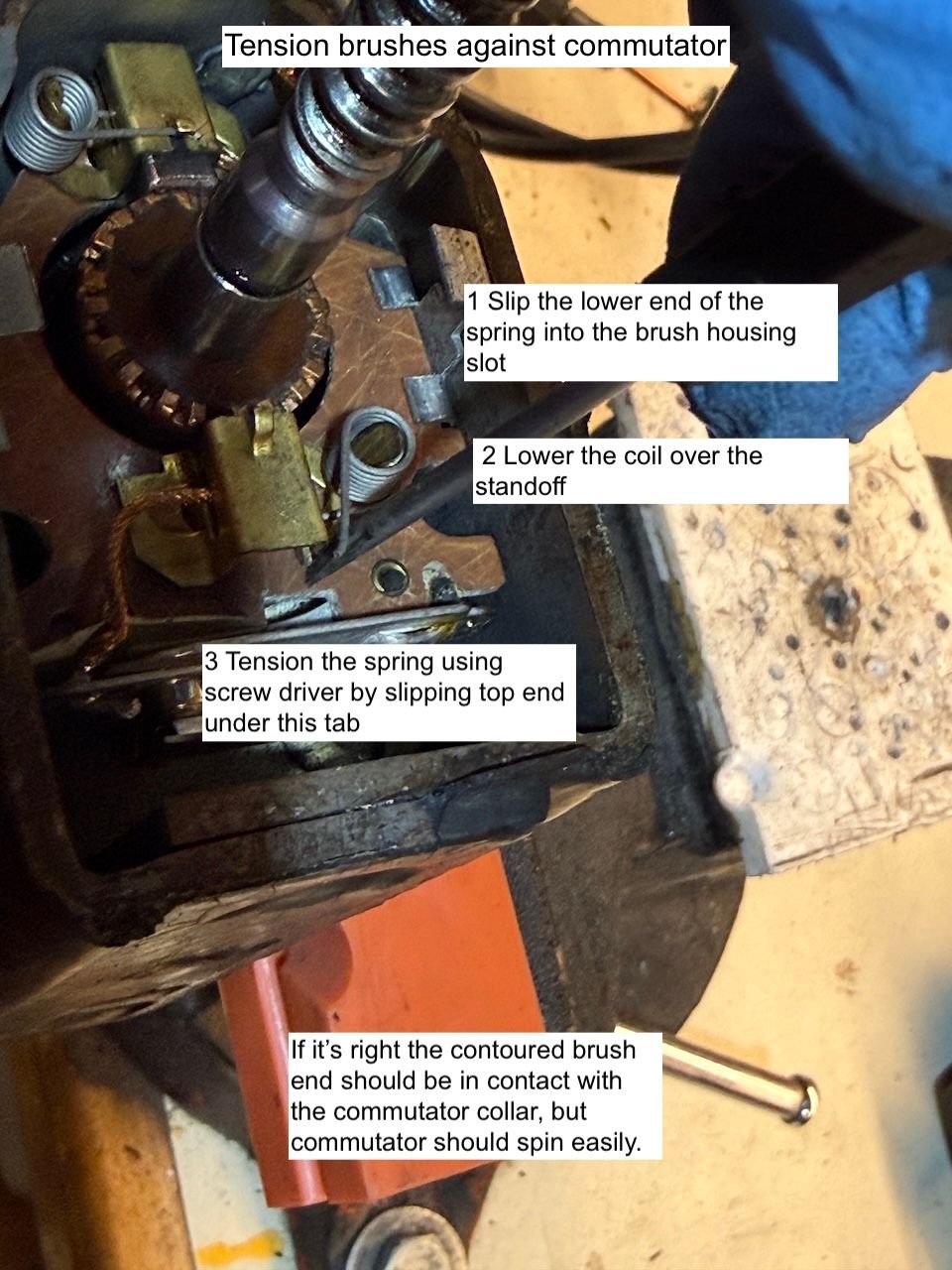 Tension springs hold the brushes against the commutator. I used a small screwdriver - bottom of spring slides against the rear of the brush, top of the spring is hooked under the tab on the brass housing. 
