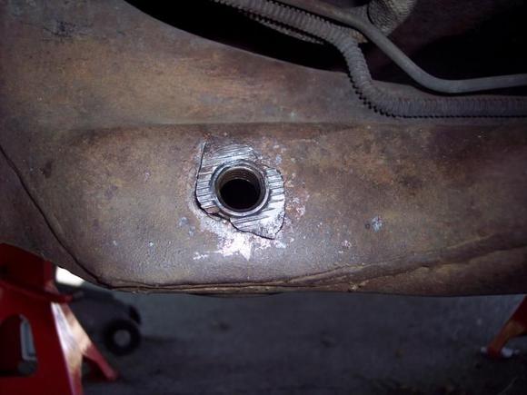 Closeup of failed attachment.  Nut and surrounding metal had pulled-away from crossmember.  Piece was put back in crossmember to show how it looked.