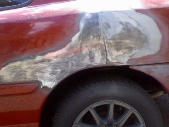 big dent in side of car, paint sanded off to bare metal(left)