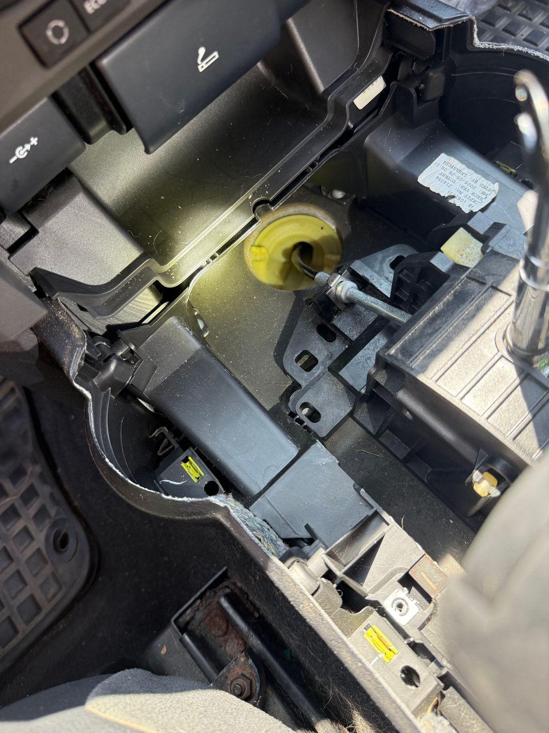 Once the cover is removed, showing the cable from the shifter, the clip, and the route through the plastic bulkhead