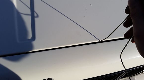 Fish your hook inside under the hood and through your window underneath and perhaps a flashlight get it hooked, then carefully drag it to the right until it pops.