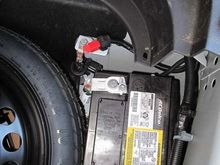 The battery cables in the back spare tire well . 