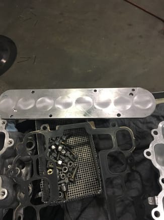 This is image of fabricated 1/4" steel block-off plate used to cover ports inside upper intake manifold plenum while series  ACIS butterfly valve assembly is removed for extrude-honing .Notice two extra holes  bored about 3/16"  to accommodate registration  pins for butterfly valve assembly, thereby permitting steel plate to fully seal over  the upper intake ACIS ports