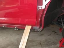I put shims (gotten at Home Depot) under the closed door to hold the door in place while all four hinge bolts were removed to install the fender bar. I never opened the door after removing the bolts.