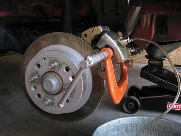 Since the caliper is rotated up and out (with the pads removed) a 6 C-clamp is used to hold the piston in while the system is bled. Notice that the caliper has to rotate far enough so the bleed bolt is above horizontal (facing upwards slightly).