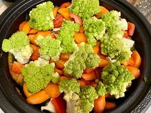 Layer of onions and minced lemon rind, then the layer of five chicken thighs, carrots, bell pepper, romanesco, salt, pepper, and a spoon of honey. 