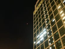 A poor photograph taken on the  outside walkway beside the Conrad Tokyo. The red dot in the middle is the full lunar eclipse. Magnificent. Quite a few people in the area were looking up also 