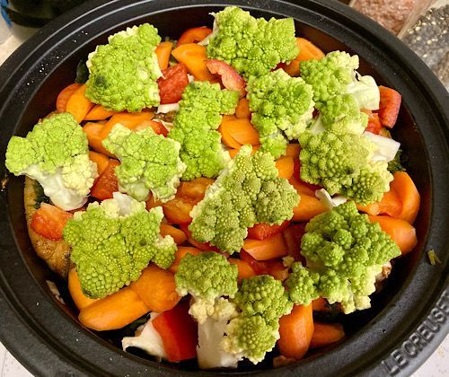 Layer of onions and minced lemon rind, then the layer of five chicken thighs, carrots, bell pepper, romanesco, salt, pepper, and a spoon of honey. 