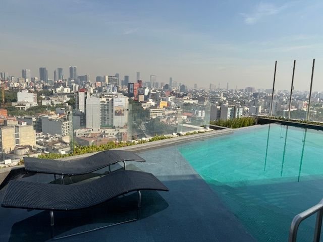 Small, rooftop pool at the Andaz with nice views of the city. A bar with large windows looking all around the city is next to it.