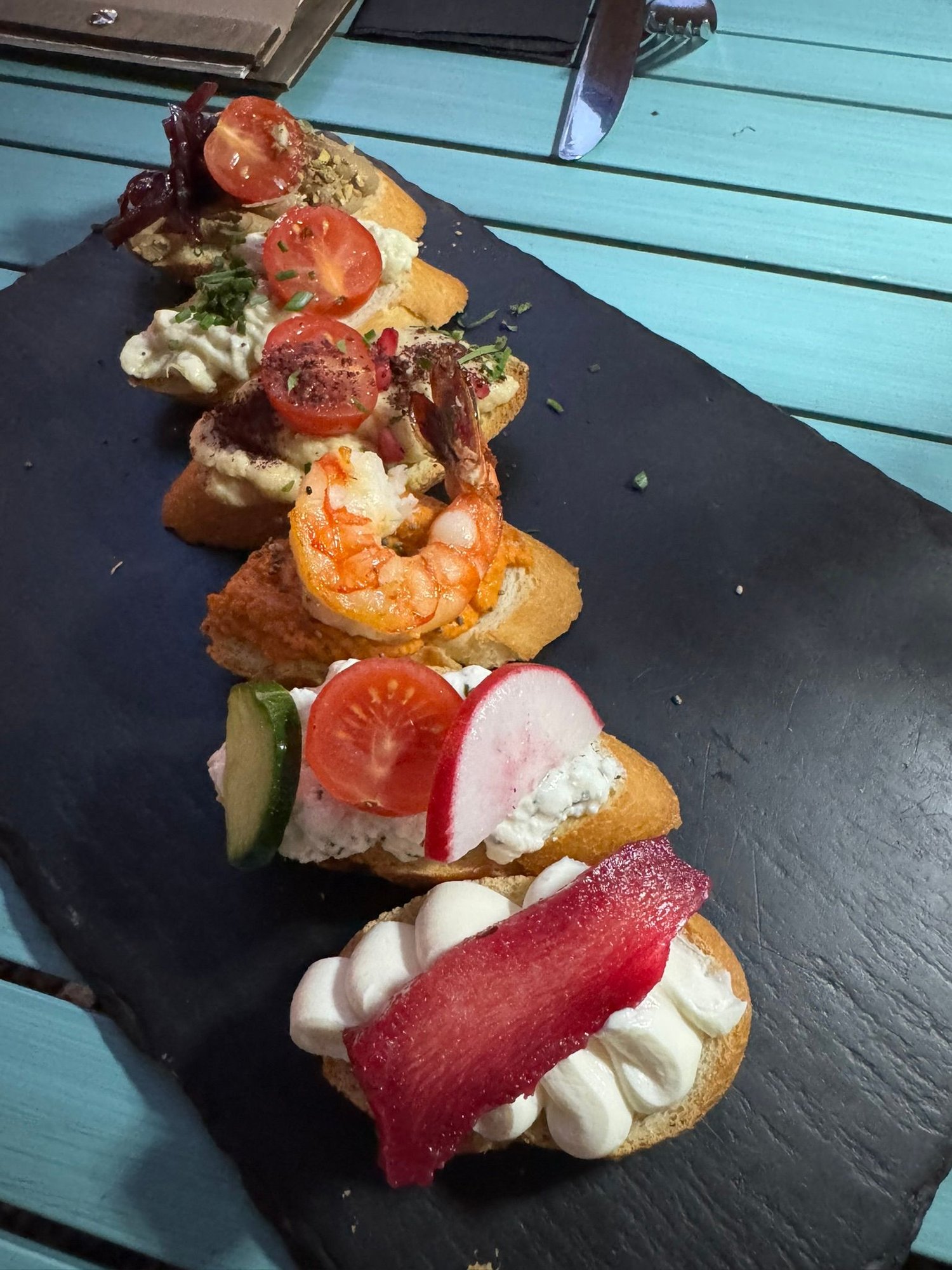 Our delicious appetizer - bruschetta with various toppings, such as cheese, humus, pate, and shrimp