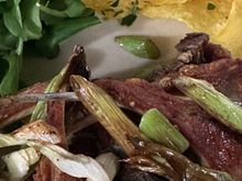 Astoundingly great little lamb chops, topped with roasted garlic scapes and accompanied by chips of potato and an arugula-type green