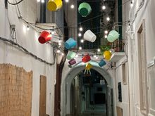 Gaily colored buckets hang over a whitewashed lane in Fasano