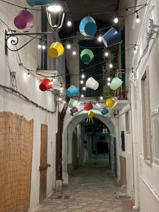 Gaily colored buckets hang over a whitewashed lane in Fasano