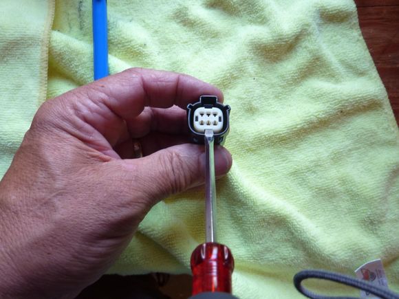 using a small flat blade screw driver pop the plastic insert out about an 1/8".  By doing this you can push the wires forward from behind to take the tension off the pin latches.