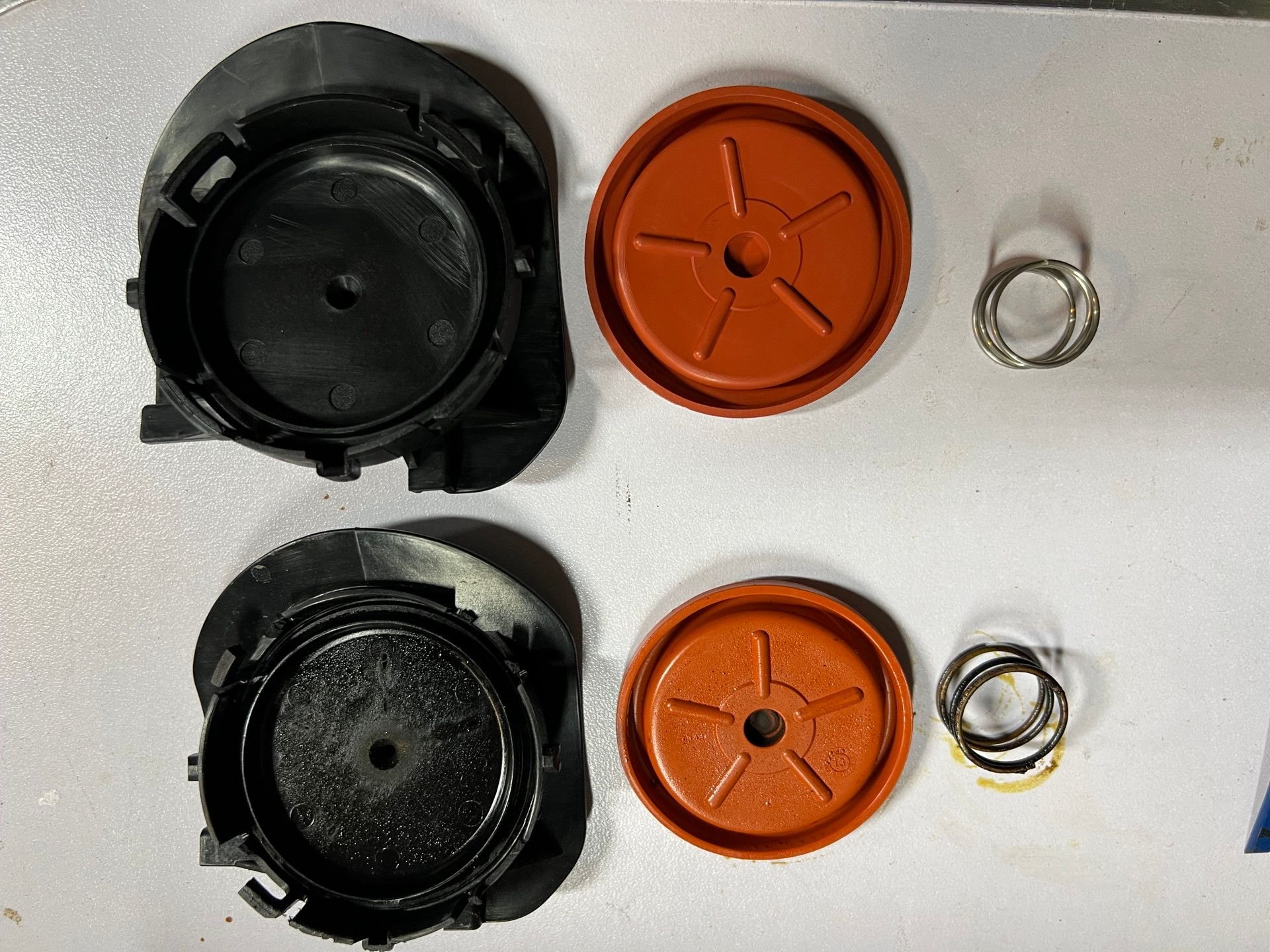 Old cap and diaphragm with spring is lower. Note the broken clips from the sacrificial cap.