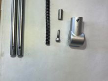 I manufactured (from a stainless 10-32 bolt) a pin to replace the stupid roll pin from stock and threaded the hole in the housing.  That little stub shaft (above my pin) goes in the strut before the spring a spacer that takes up space and compresses the spring more.  It was TWICE as long as this and the struts were almost impossible to compress.  It's like they bored the shafts too deep and had to add the spacer - then calibrated it to make the struts almost uncomprressable.  