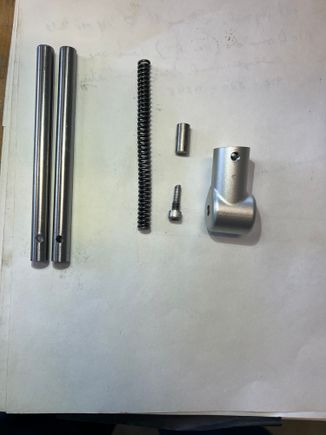 I manufactured (from a stainless 10-32 bolt) a pin to replace the stupid roll pin from stock and threaded the hole in the housing.  That little stub shaft (above my pin) goes in the strut before the spring a spacer that takes up space and compresses the spring more.  It was TWICE as long as this and the struts were almost impossible to compress.  It's like they bored the shafts too deep and had to add the spacer - then calibrated it to make the struts almost uncomprressable.  