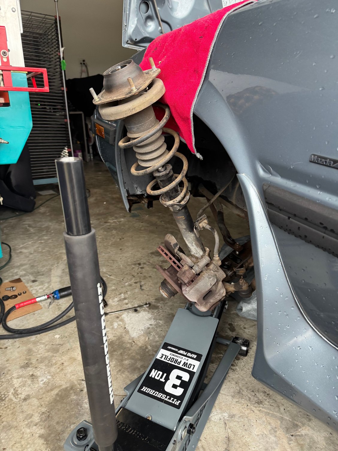 Undo 3 bolts from the top hat and get your jack under here, to hold the assembly in place, watch your brake lines!! Compress the spring and remove.