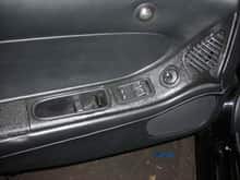 The door armrest plastic was metalized and painted, while the panels were covered in black leather.  The air vent surround is also metalized and painted wrinkle finish black and each individual slat in the vent was taken out and actually chrome plated over the copper and nickel.  This picture shows the only parts inside the car that are not metal, wool, or leather, and they are the door handle area, the window switches, and the mirror switch.   (kd101)