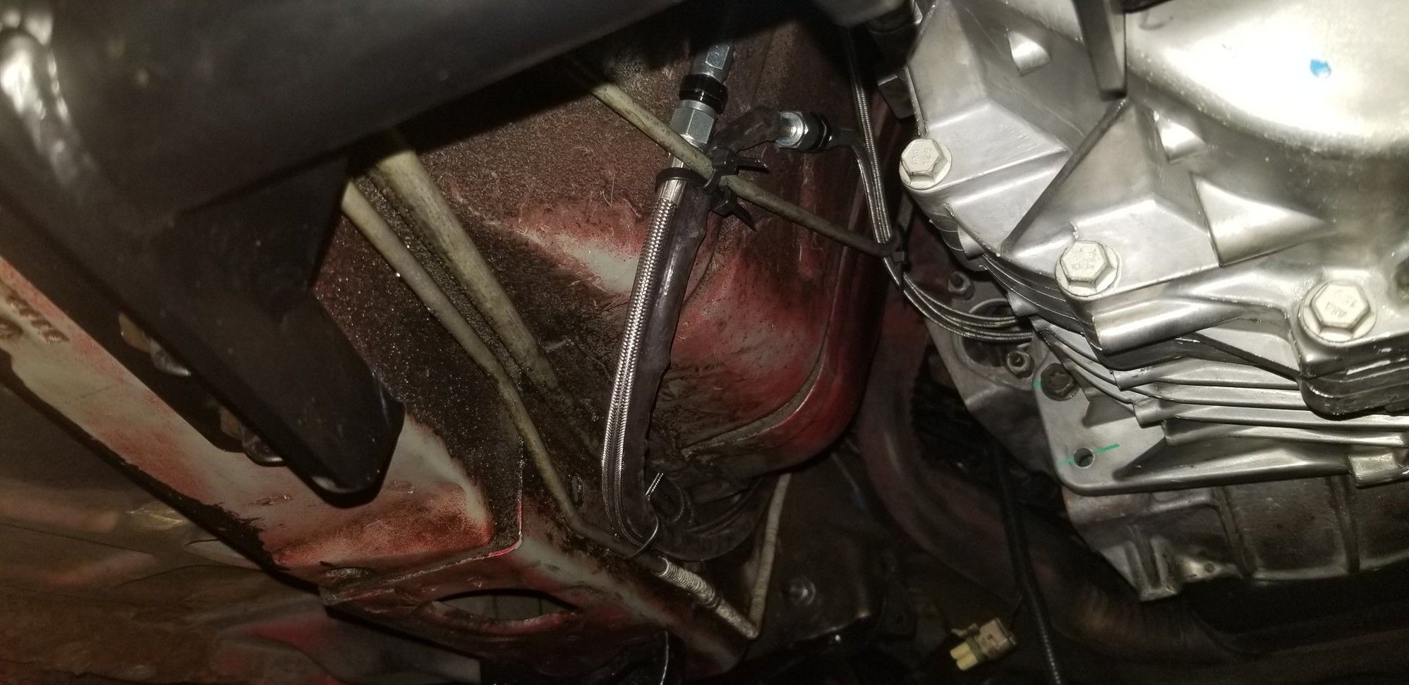 Heres the clutch lines coming out of the back of the S10 slave cyl mount.  The black sheathed one is for the clutch master (lower fitting), while the bare stainless one is the speed bleeder (upper fitting)