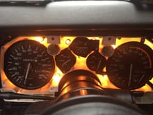 Gauge cluster with (more than likely) original incandescent bulbs installed.  Only the bulb to the top left behind speedometer is burnt out.