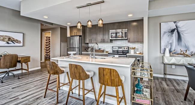 Apartment kitchen with stainless steel appliances, quartz countertops and wood-style flooring.